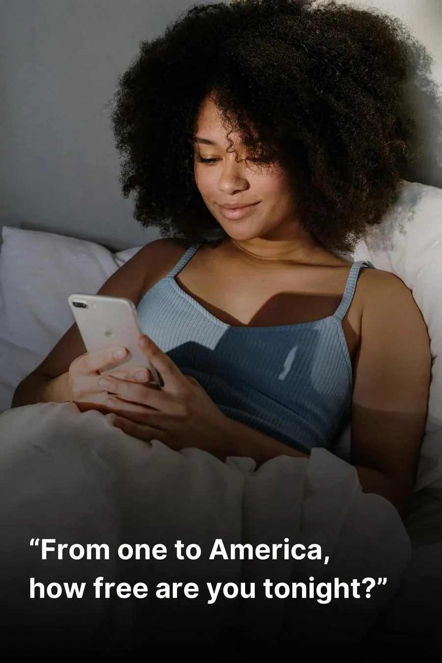 Mujer acostada en la cama y sonriendo mientras le escribe a alguien por el teléfono