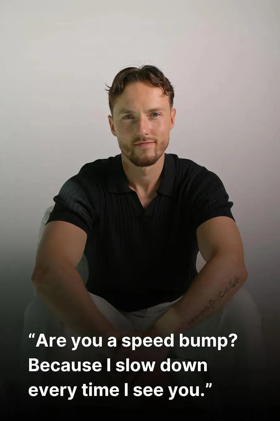 A confident man is sitting and wearing a black shirt.