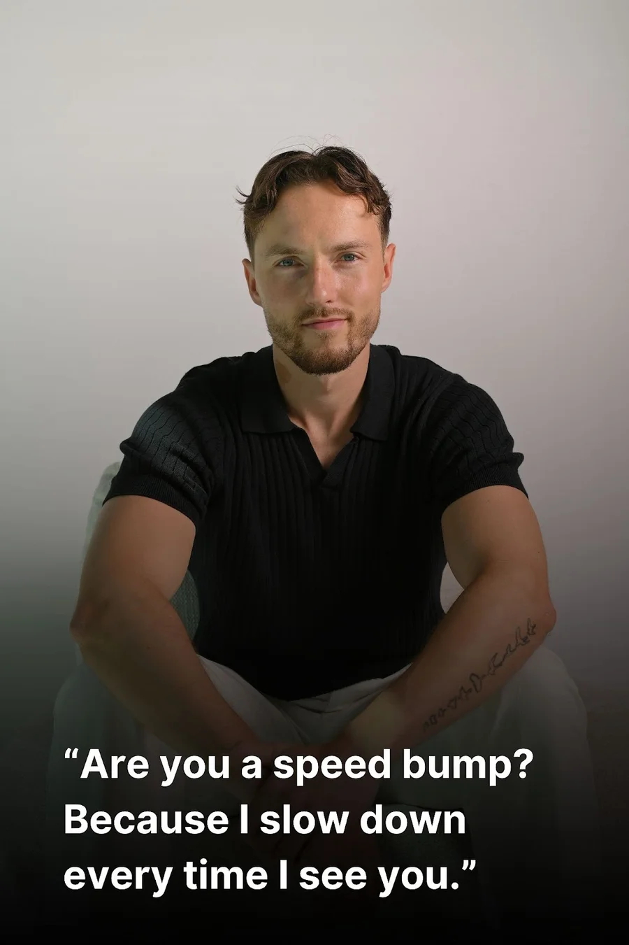A confident man is sitting and wearing a black shirt.