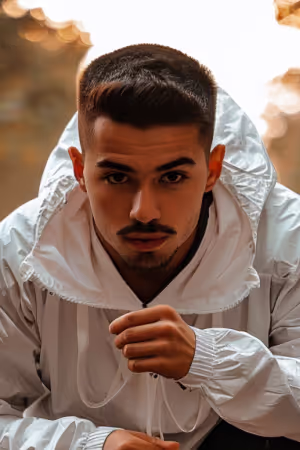 Ein stilvoller Mann in weißer Jacke und Hoodie, der auf seinem KI-gestützten Profilbild der Dating-App ansprechbar aussieht.